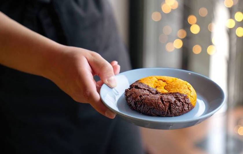 A Keksi & Co team member holding a cookie on a plate
