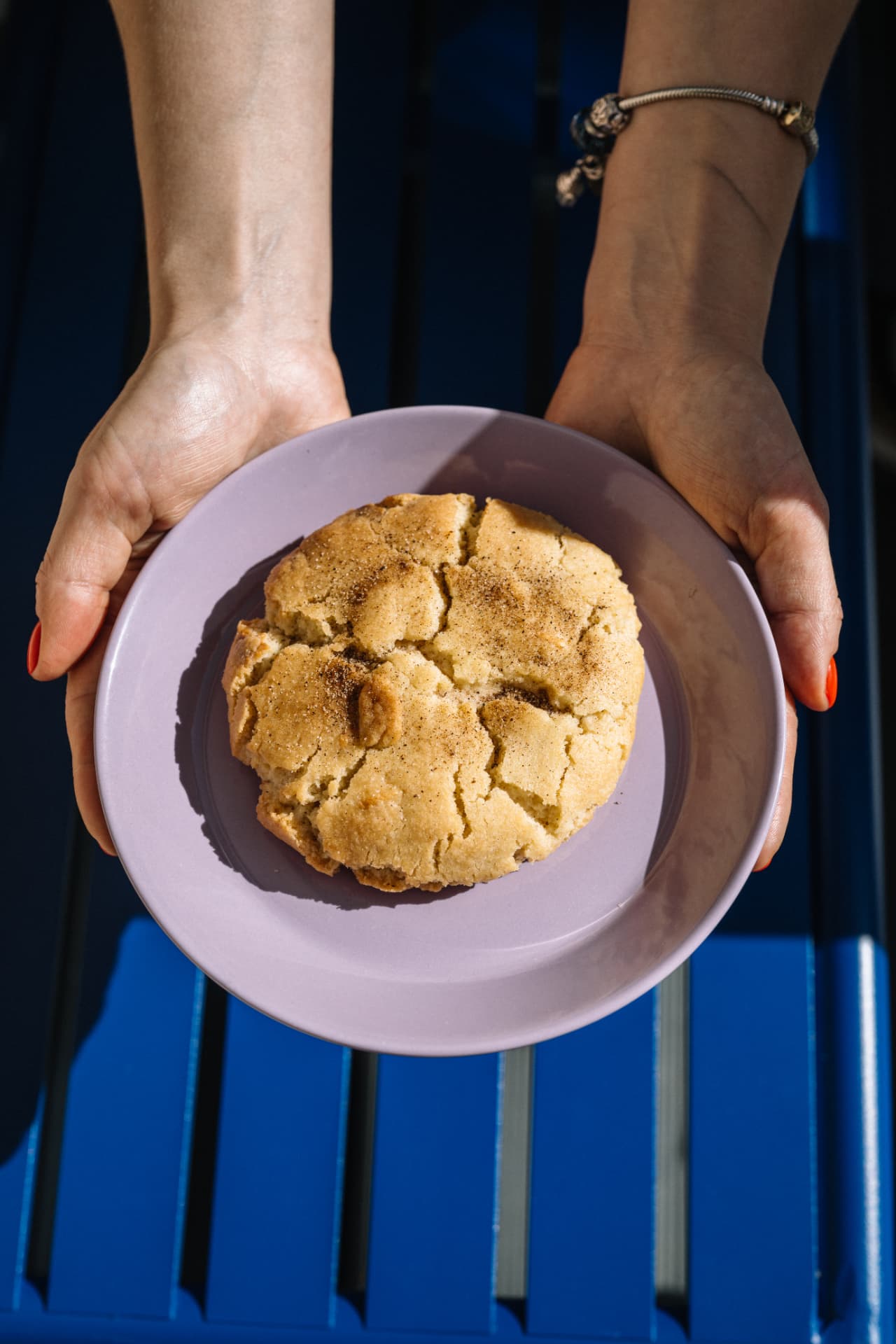 Hands holding a large cookie on a lilac plate